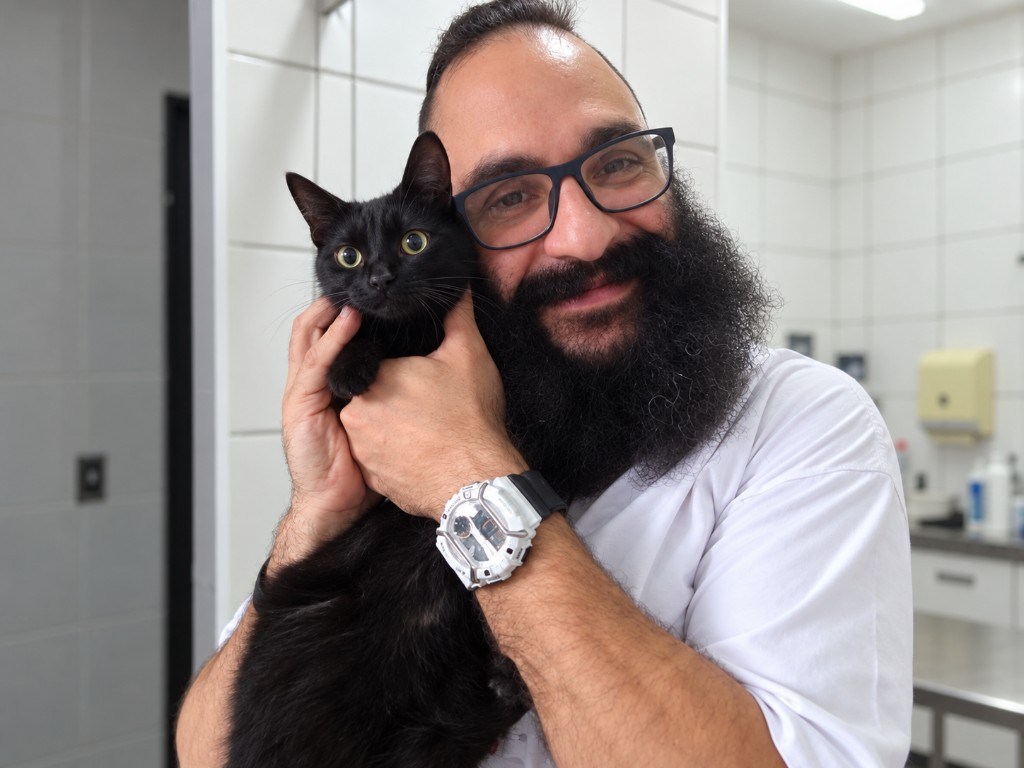 Dr. Saulo Godoy Chigo segurando um gato preto na clínica veterinária